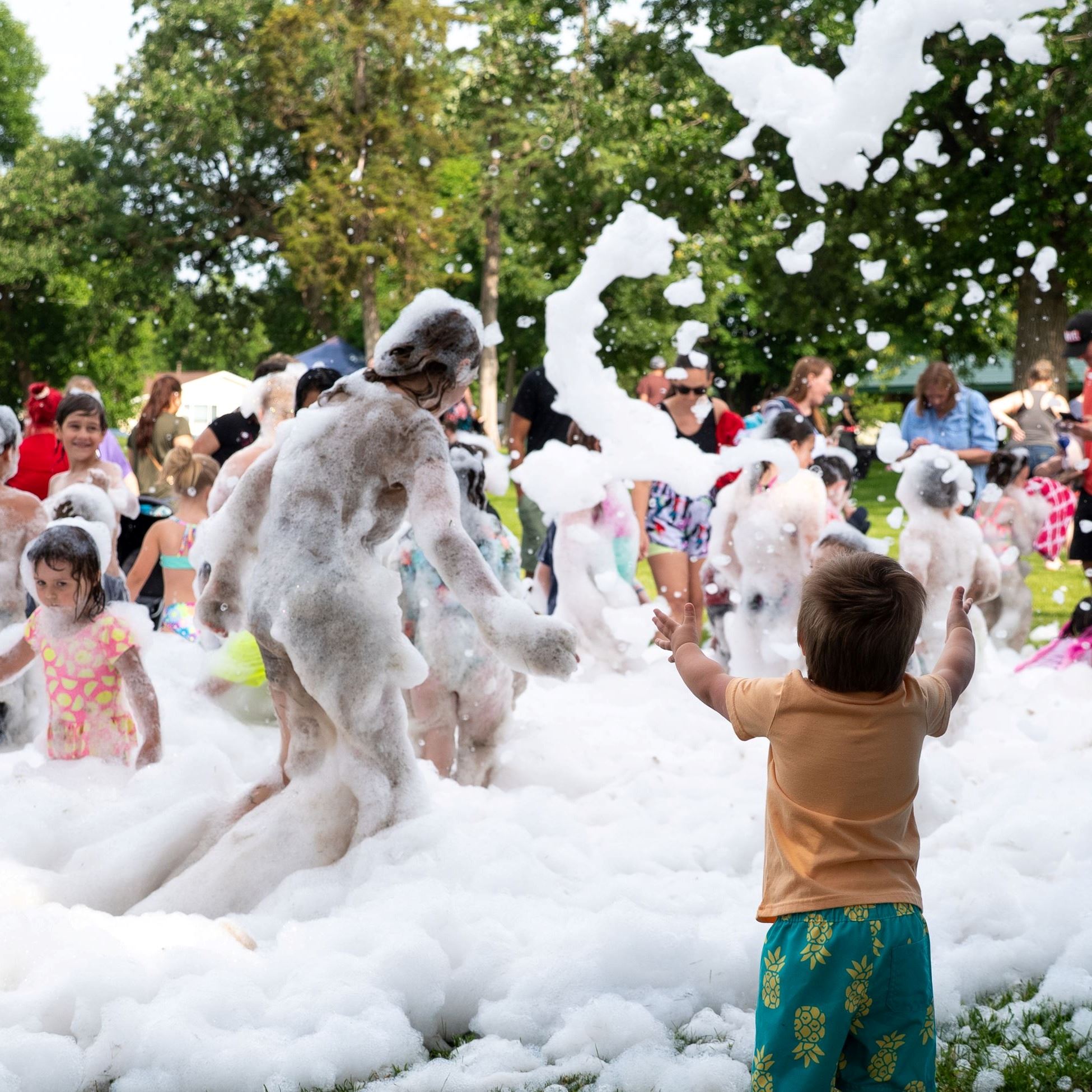 Parent reaching for child to join foam party.